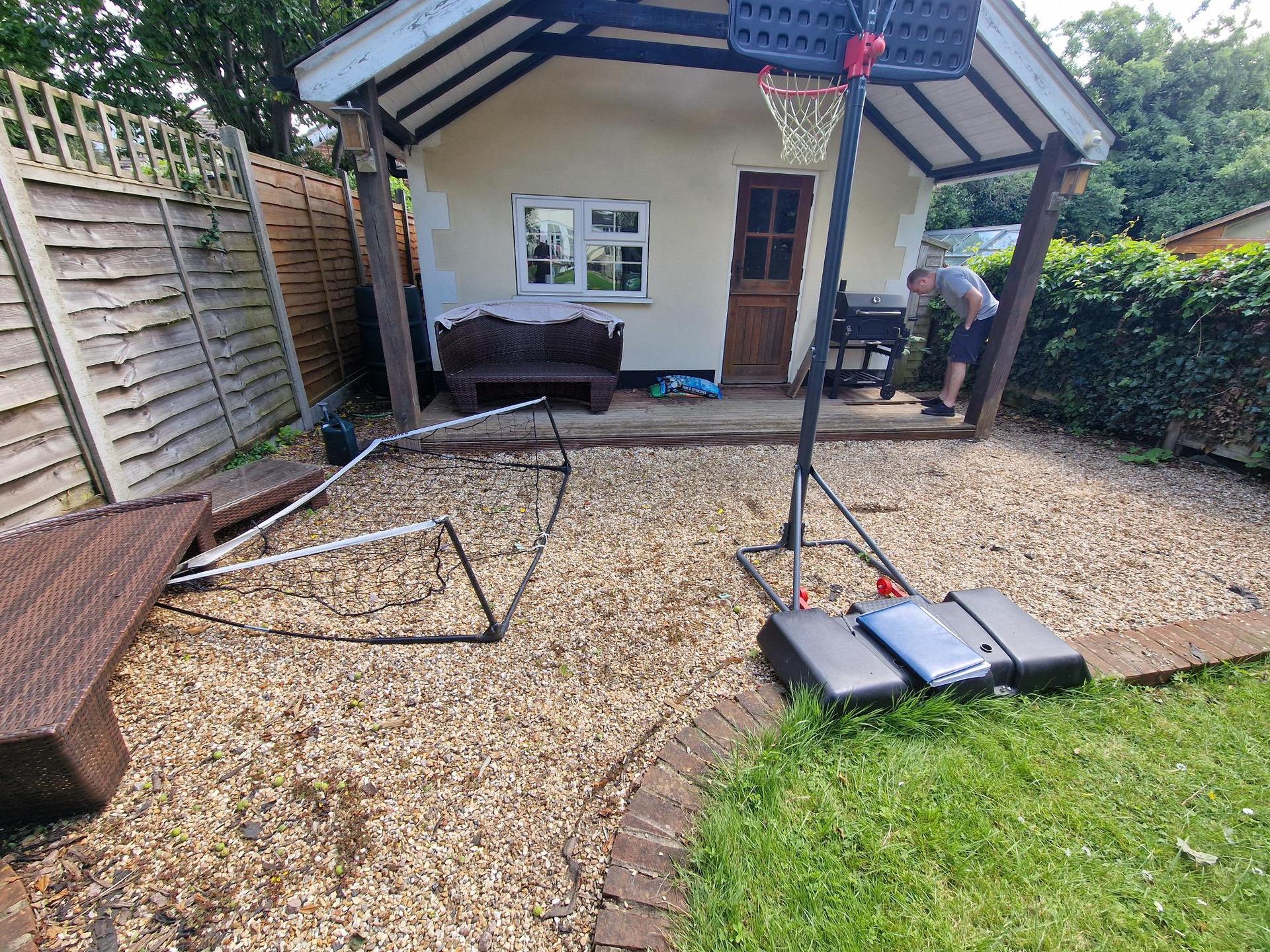 Shingle area in front of garden summerhouse with basket ball net in foreground.