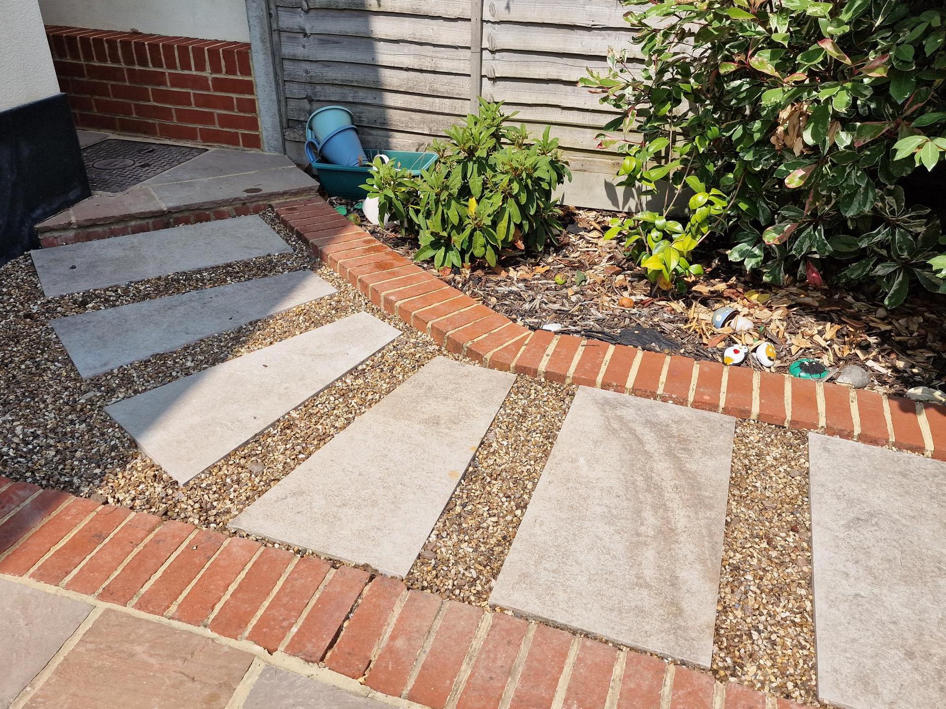 Slab pathway with shingle and red brick edging.